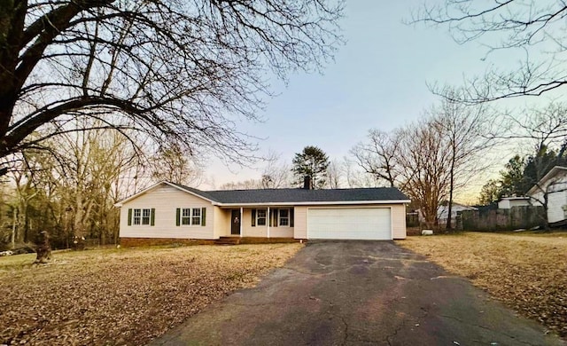 ranch-style home with aphalt driveway, fence, and an attached garage