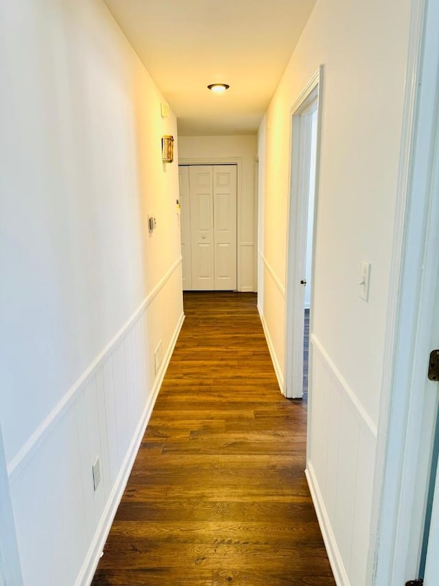 hallway with a wainscoted wall and dark wood-type flooring