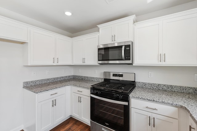 kitchen with stainless steel appliances, white cabinets, and light stone counters