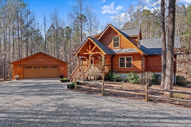 log-style house featuring a detached garage, log siding, roof with shingles, an outbuilding, and fence