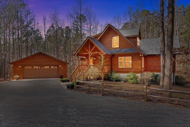 view of front of home with an outdoor structure, fence, a detached garage, and log siding