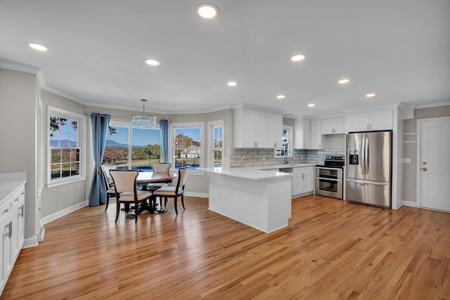 kitchen with white cabinetry, stainless steel appliances, ornamental molding, decorative light fixtures, and kitchen peninsula