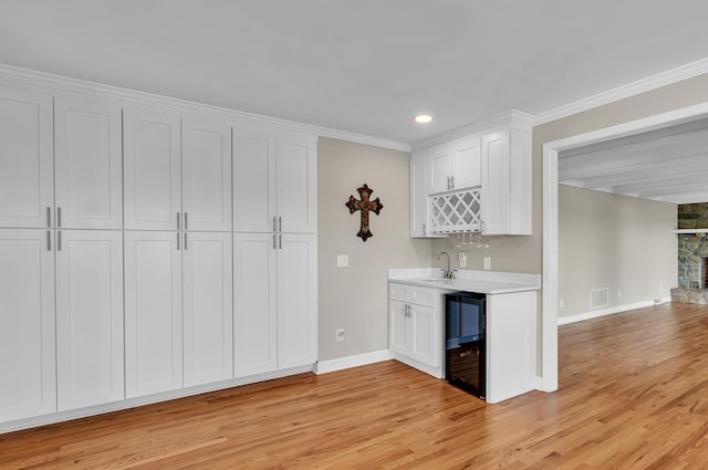 kitchen with white cabinetry, sink, wine cooler, and light hardwood / wood-style floors