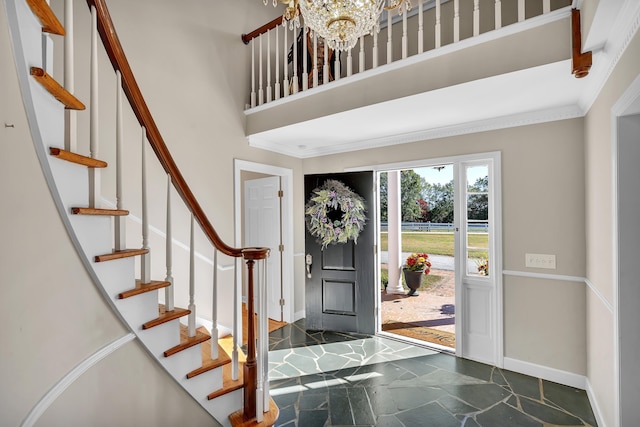 foyer featuring a towering ceiling, ornamental molding, and a chandelier