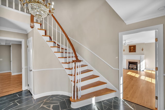 stairway featuring crown molding, wood-type flooring, and a brick fireplace