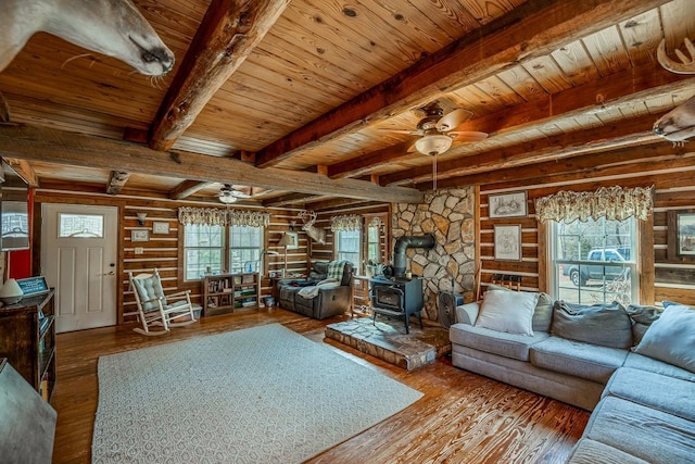 living room with wood-type flooring, a wood stove, ceiling fan, wooden ceiling, and beam ceiling