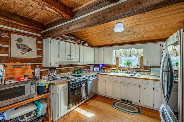 kitchen with appliances with stainless steel finishes, tile countertops, white cabinetry, wood ceiling, and light hardwood / wood-style flooring