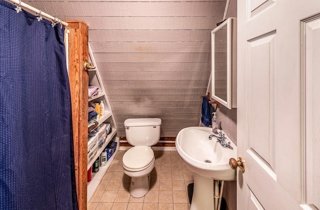 bathroom with wooden walls, toilet, curtained shower, and tile patterned flooring