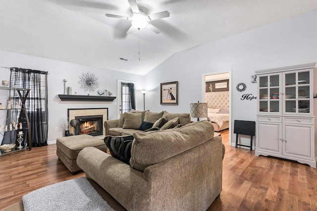 living room featuring ceiling fan, lofted ceiling, hardwood / wood-style floors, and a textured ceiling