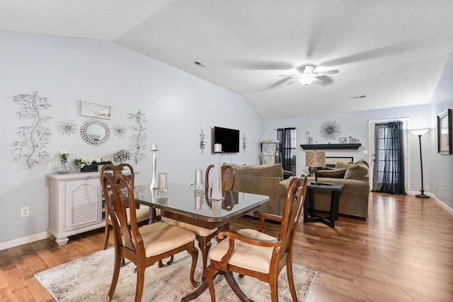 dining space featuring ceiling fan, wood-type flooring, and vaulted ceiling