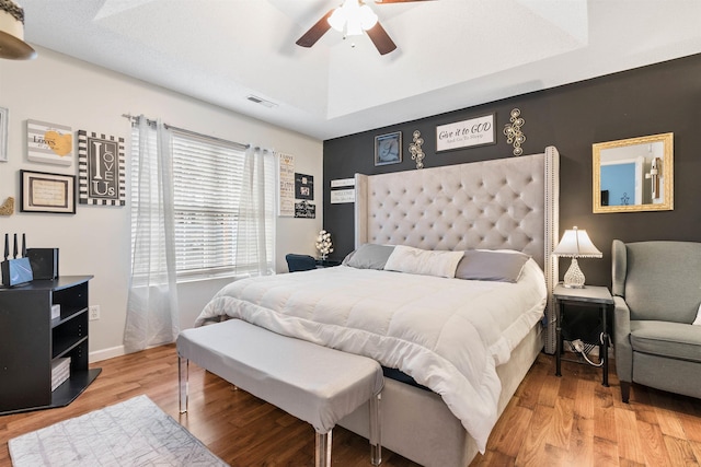 bedroom featuring wood-type flooring, ceiling fan, and a tray ceiling