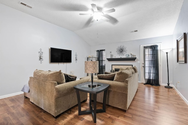 living room featuring hardwood / wood-style flooring, ceiling fan, lofted ceiling, and a textured ceiling