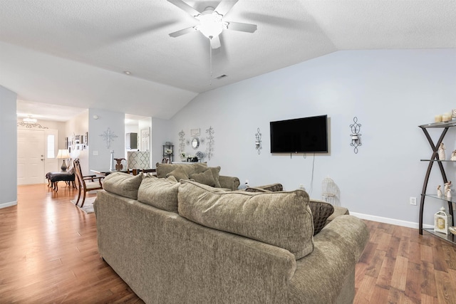 living room featuring lofted ceiling, ceiling fan, wood-type flooring, and a textured ceiling