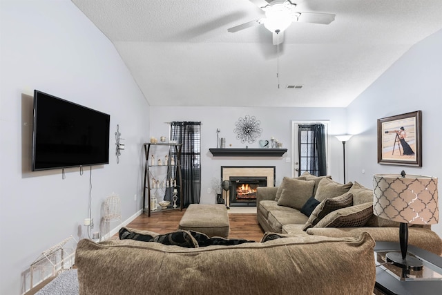 living room with ceiling fan, hardwood / wood-style flooring, vaulted ceiling, and a textured ceiling