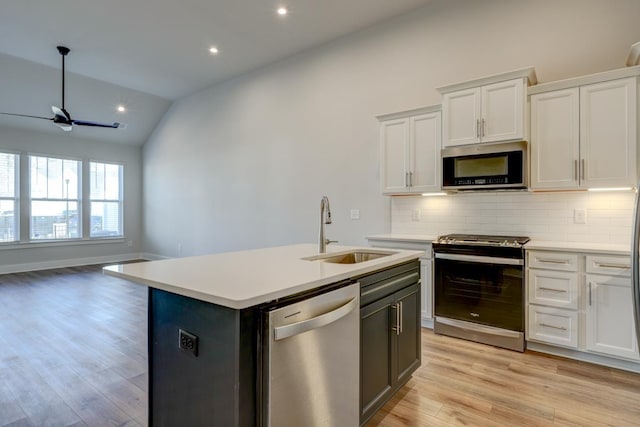 kitchen featuring sink, appliances with stainless steel finishes, an island with sink, white cabinets, and vaulted ceiling