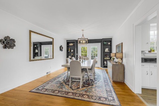 dining space featuring ornamental molding, french doors, and light wood-type flooring