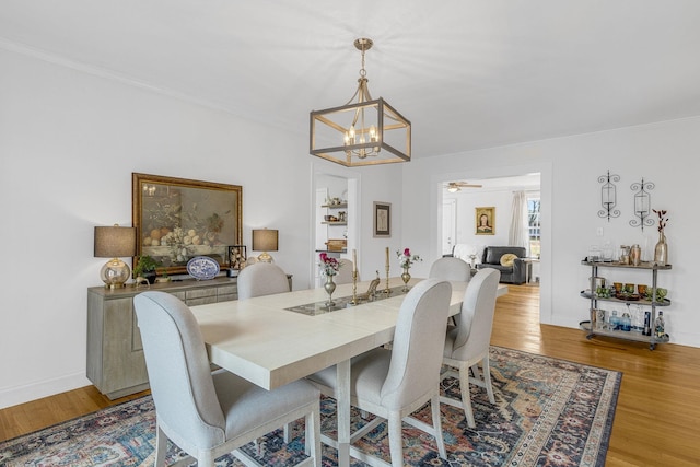 dining space with crown molding, ceiling fan with notable chandelier, and light wood-type flooring