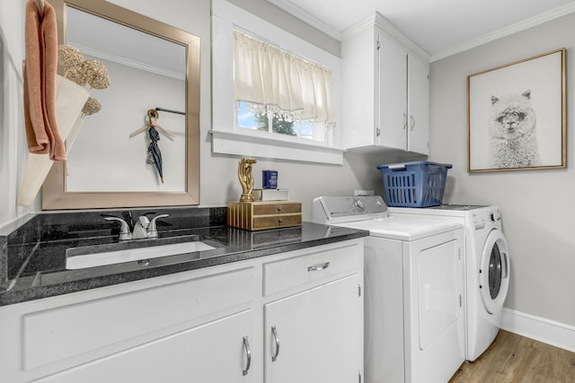 washroom with crown molding, cabinets, washer and clothes dryer, and sink