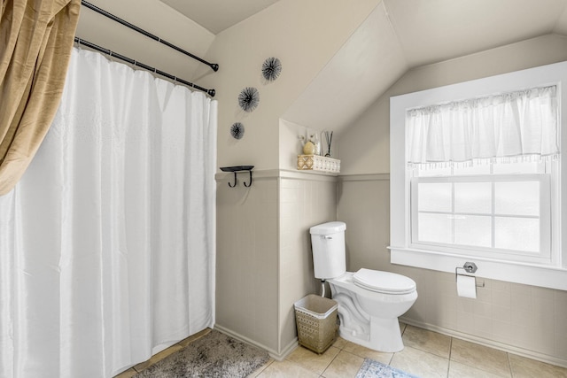 bathroom featuring tile patterned floors, toilet, a shower with curtain, vaulted ceiling, and tile walls