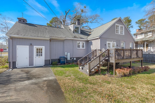 back of house featuring a wooden deck and a lawn