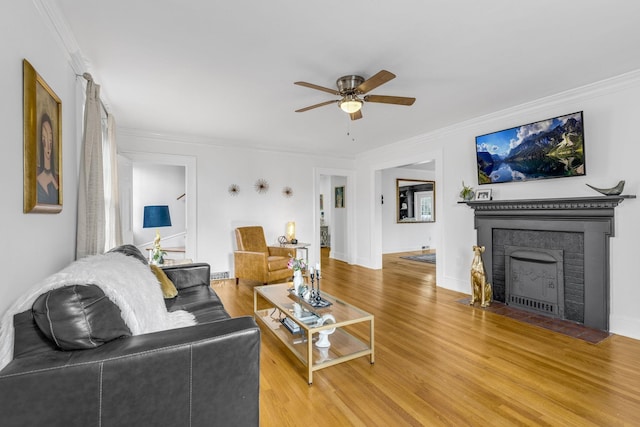 living room with hardwood / wood-style flooring, crown molding, and ceiling fan