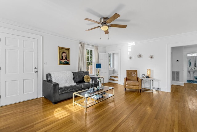 living room with hardwood / wood-style flooring, ceiling fan, and crown molding