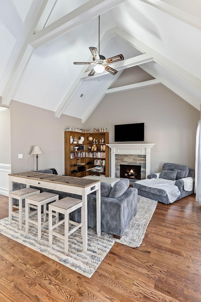 living room featuring hardwood / wood-style flooring, ceiling fan, a fireplace, and lofted ceiling with beams