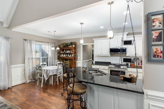 kitchen with sink, white cabinetry, dark hardwood / wood-style floors, pendant lighting, and stainless steel appliances