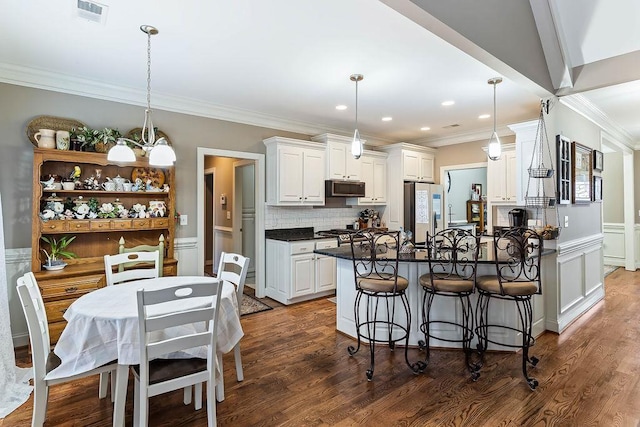 kitchen with dark hardwood / wood-style floors, appliances with stainless steel finishes, decorative light fixtures, and white cabinets