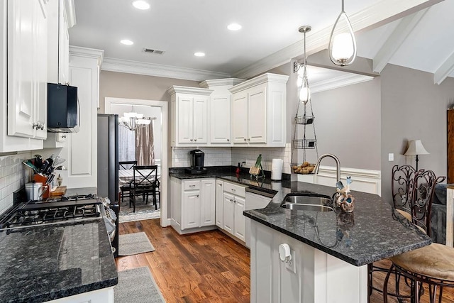 kitchen featuring white cabinetry, sink, a kitchen breakfast bar, hanging light fixtures, and kitchen peninsula