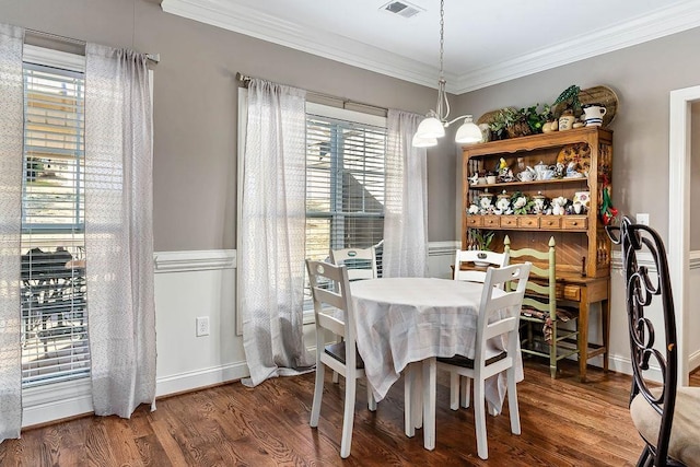 dining room with dark wood-type flooring, ornamental molding, and a chandelier