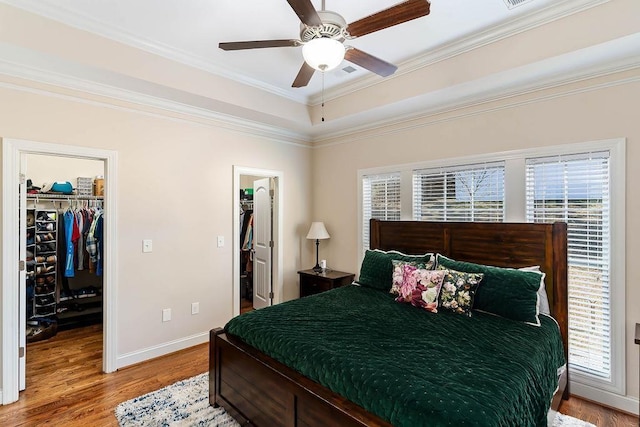 bedroom featuring multiple windows, wood-type flooring, a spacious closet, and a closet