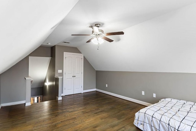 unfurnished bedroom with ceiling fan, dark hardwood / wood-style floors, vaulted ceiling, and a closet