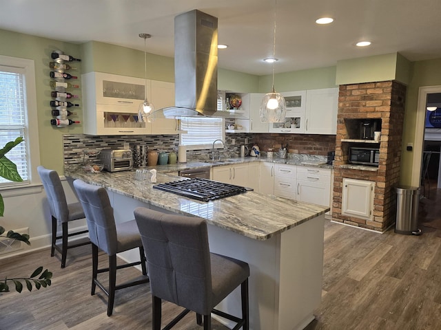 kitchen featuring white cabinetry, a breakfast bar area, hanging light fixtures, island exhaust hood, and kitchen peninsula