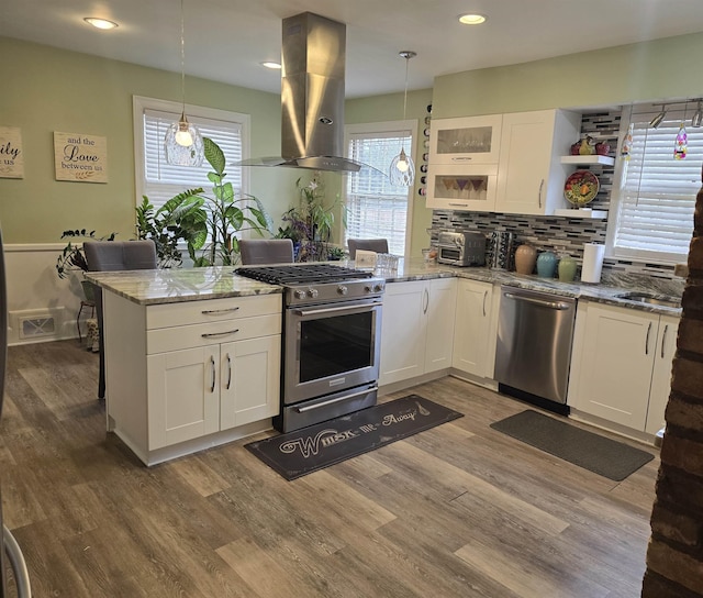 kitchen with white cabinetry, hanging light fixtures, island range hood, and appliances with stainless steel finishes