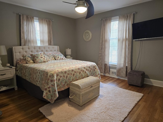 bedroom featuring multiple windows, dark hardwood / wood-style floors, and ceiling fan