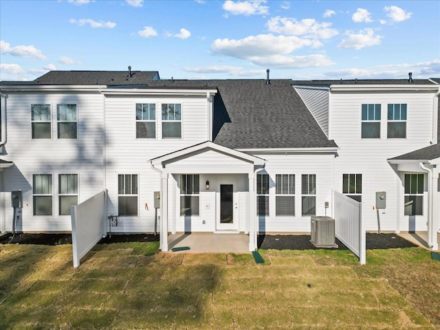 rear view of house with cooling unit, a lawn, and a patio