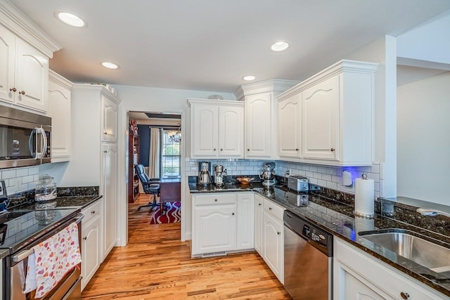 kitchen featuring sink, dark stone countertops, stainless steel appliances, light hardwood / wood-style floors, and white cabinets