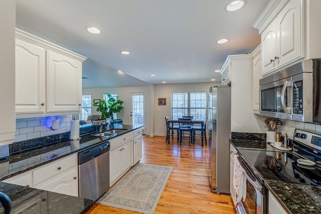 kitchen with appliances with stainless steel finishes, sink, white cabinets, and light hardwood / wood-style flooring