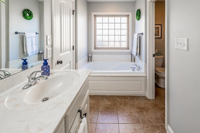 bathroom featuring tile patterned floors, vanity, toilet, and a bathing tub