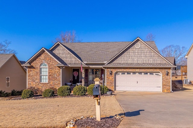 ranch-style house featuring a garage, covered porch, and central air condition unit