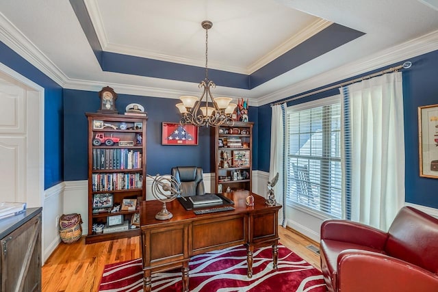 office with a notable chandelier, a tray ceiling, ornamental molding, and hardwood / wood-style flooring