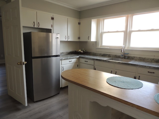 kitchen featuring stainless steel refrigerator, sink, hardwood / wood-style floors, and white cabinets