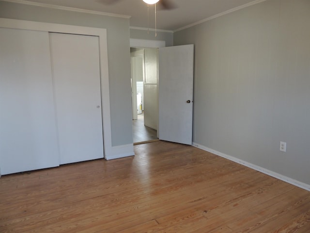 unfurnished bedroom with ornamental molding, ceiling fan, light wood-type flooring, and a closet