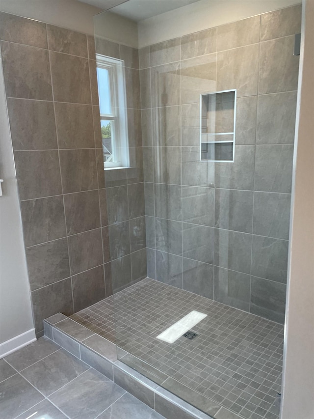 bathroom featuring tile patterned flooring and tiled shower