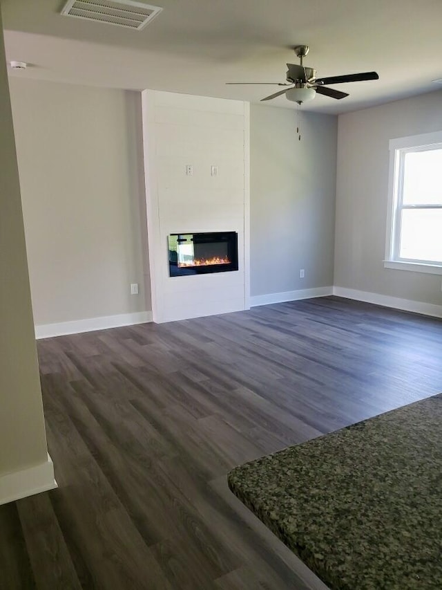 unfurnished living room with dark hardwood / wood-style flooring and ceiling fan