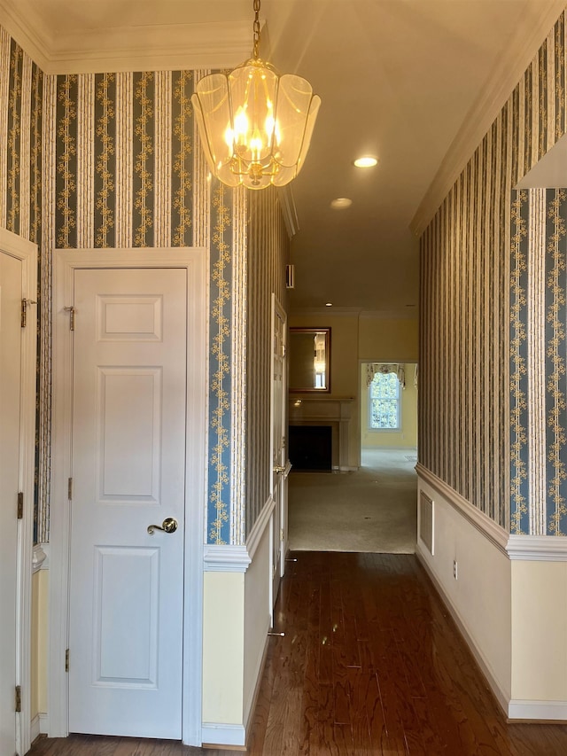 hall featuring crown molding, dark hardwood / wood-style floors, and a notable chandelier