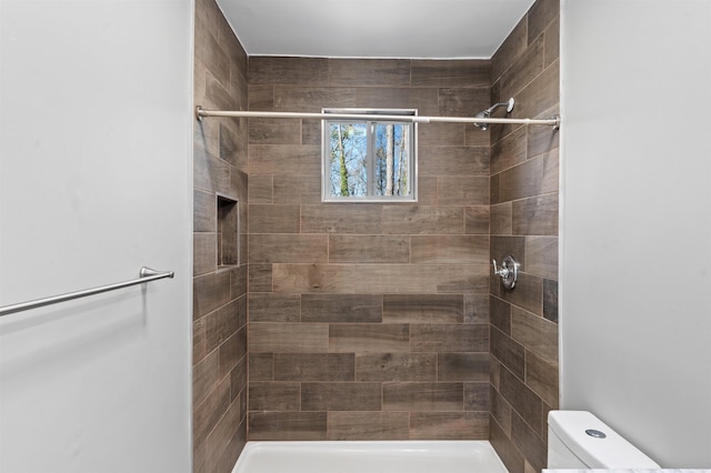 bathroom featuring toilet and a tile shower