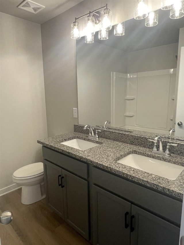 bathroom featuring vanity, wood-type flooring, a shower, and toilet