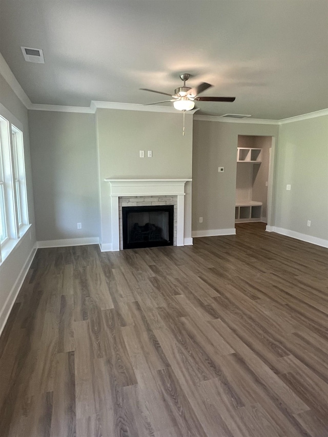 unfurnished living room featuring a tiled fireplace, crown molding, and dark hardwood / wood-style floors